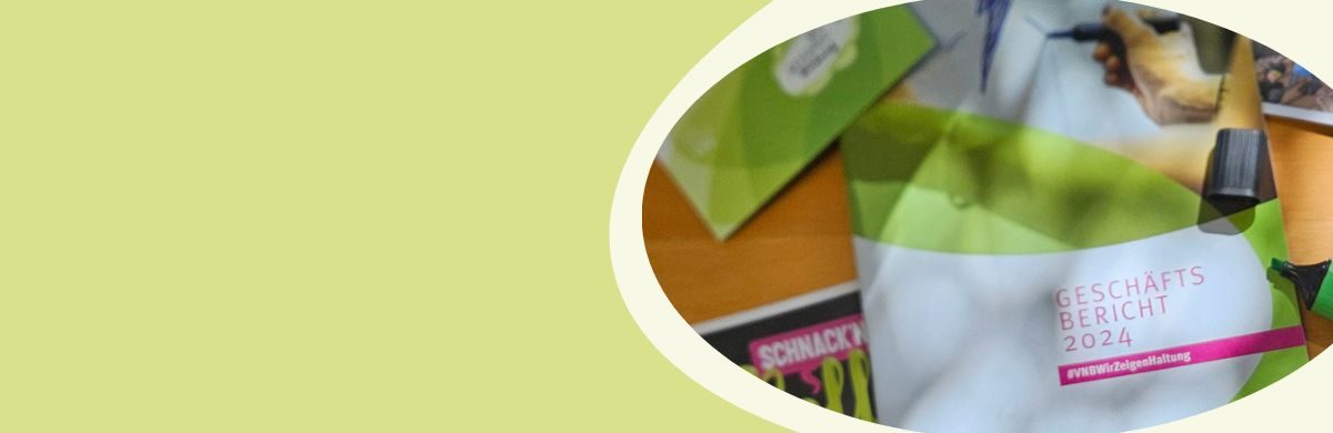 Ausschnitt eines Tisches mit mehreren Broschüren, darunter eine mit der Aufschrift 'GESCHÄFTSBERICHT 2024', und einem Stift.
