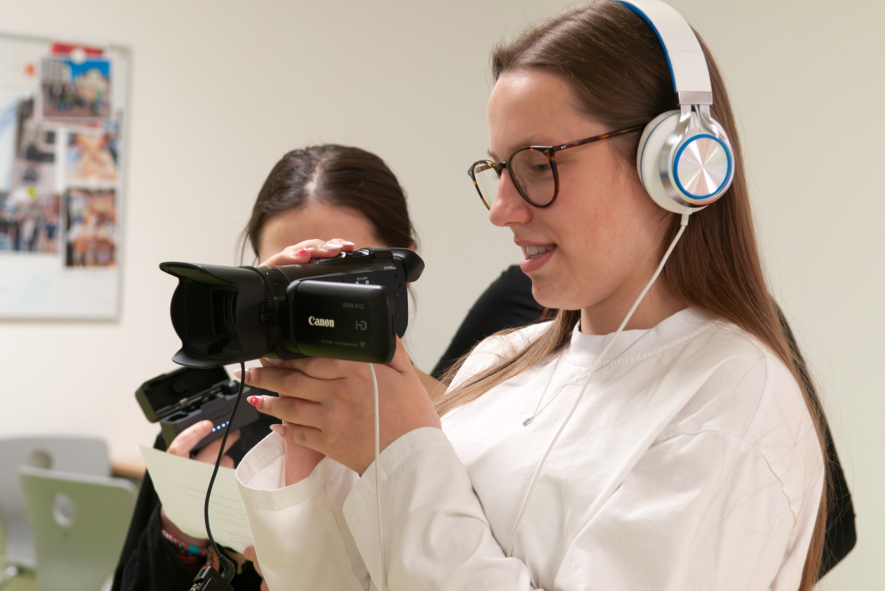 Filmaufnahmen Zwei junge Frauen bei Filmaufnahmen, eine hält eine Kamera, die andere trägt Kopfhörer und hält ein Smartphone