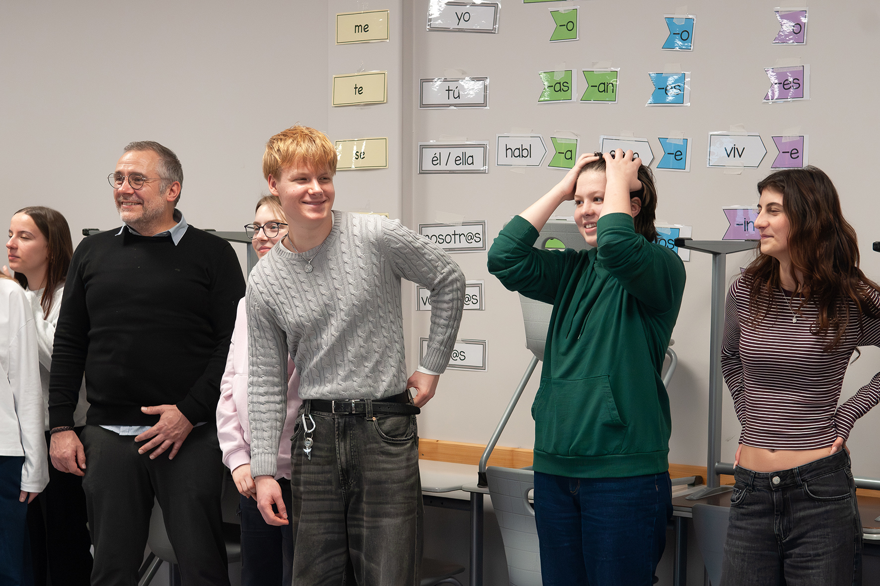Theaterpädagogische Übungen Gruppe von Jugendlichen steht vor einer Wand mit farbigen Wortkarten in Spanisch und macht gestische Übungen