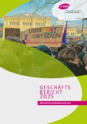 VNB Geschäftsbericht 2025. Menschenmenge bei einer Demonstration vor einem historischen Bahnhofsgebäude, eine Person hält ein Schild mit der Aufschrift 'LIEBER BUNT STATT BRAUN Demokratie verteidigen'