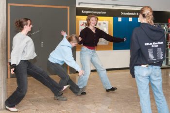 3 Schüler*innen bewegend im Klassenraum